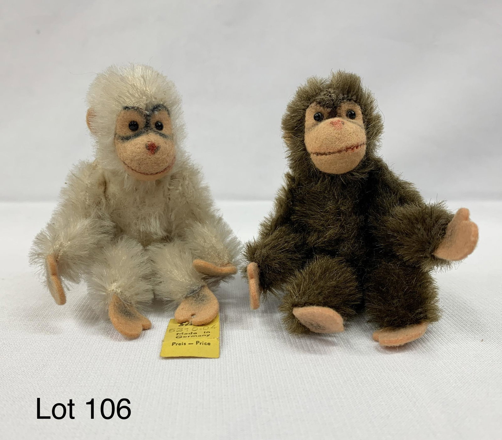 Vintage Steiff Miniature Mohair "Jocko" Monkeys: A pair of Steiff miniature "Jocko" monkey dolls with white and brown mohair fur. Both have jointed arms and legs, black bead eyes and felt hands, feet, ears and face. White monkey has original yellow 
