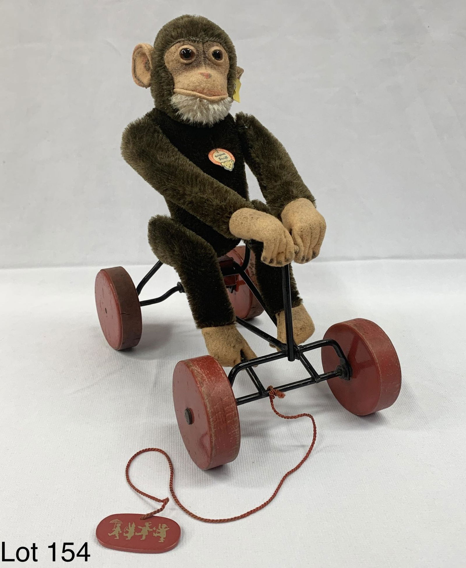 Rare Vintage Mid Century Steiff "Peter" Mohair Monkey: A vintage mid century Steiff mohair monkey doll. He is sitting on a black metal bike with red wooden wheels. He has a red pull string with "Kinderparadies (Children's Paradise)" name and address marke