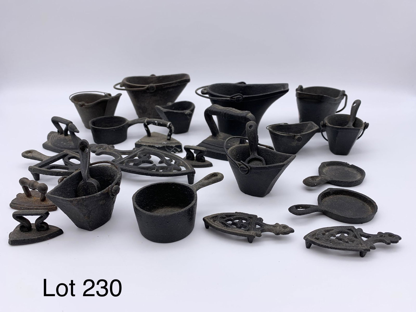 Collection of Vintage Cast Iron Miniatures: A group of vintage cast iron miniatures including coal hods, scoopers, irons, pots, pans and more. Largest coal hod is 2 1/4" tall. *notes- wear from age and some rusting.
