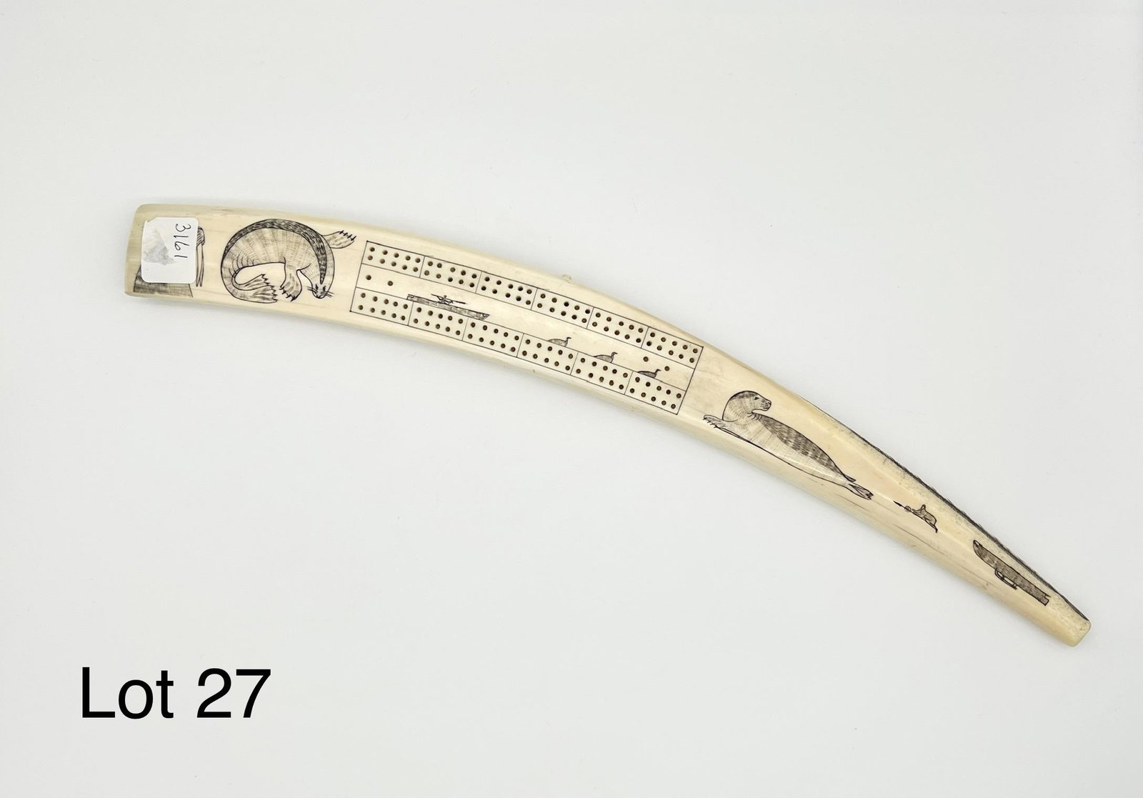Vintage Inuit Made Cribbage Board: A vintage Inuit made cribbage board. Fashioned from a walrus tusk and decorated with scrimshaw renderings of animals, fish and hunting scenes. 19" long.