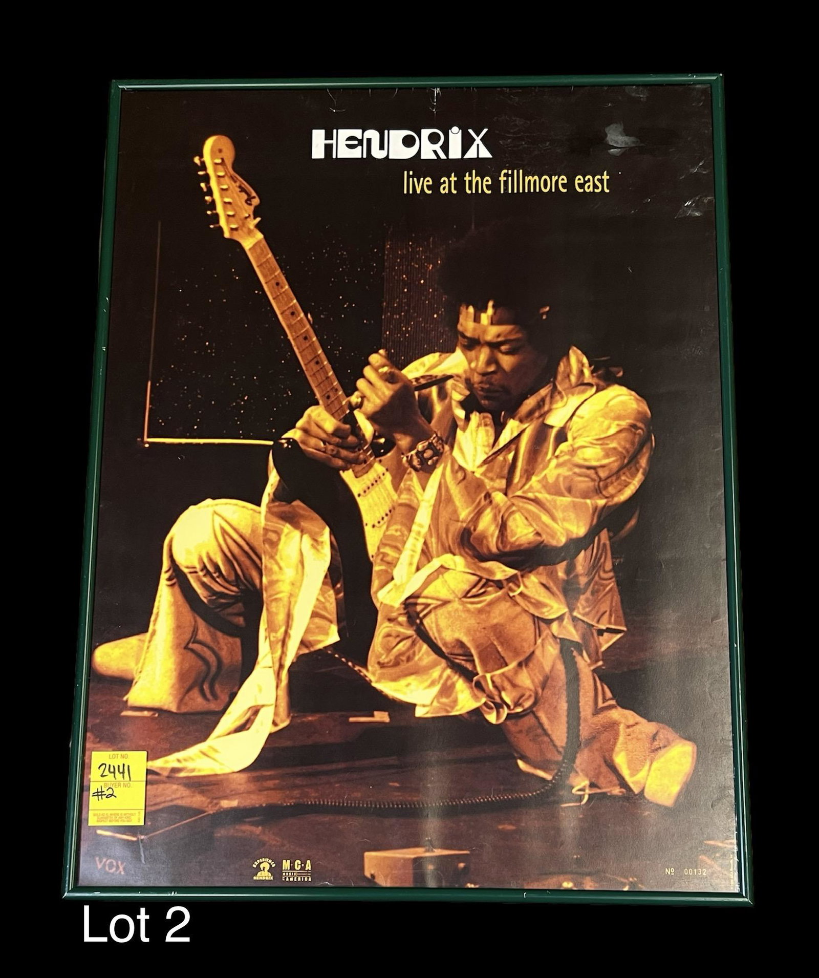 Jimi Hendrix "Live at the Fillmore East" Framed Poster: A poster of Jimi Hendrix playing guitar. The top reads "Hendrix live at the fillmore east". Dated 1999 from MCA records. Marked no. 00132 on bottom right. Presented in a green poster frame that measur