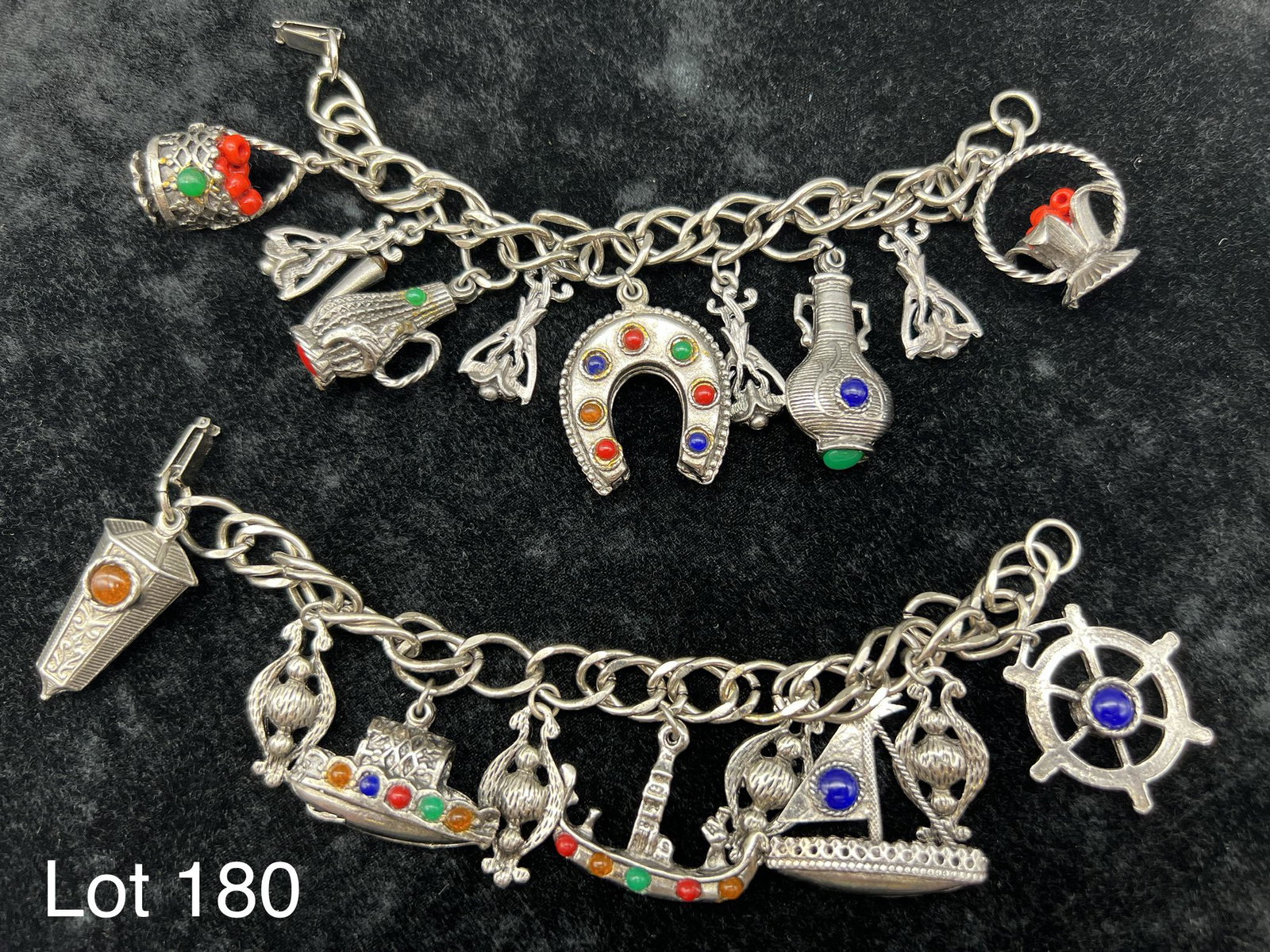 Sterling Silver and Gemstone Charm Bracelet Duo: A lot of 2 sterling silver and gemstone charm bracelets. One bracelet features a nautical theme. The other bracelets charms include horseshoe, vases and baskets. Both bracelets feature stones such as