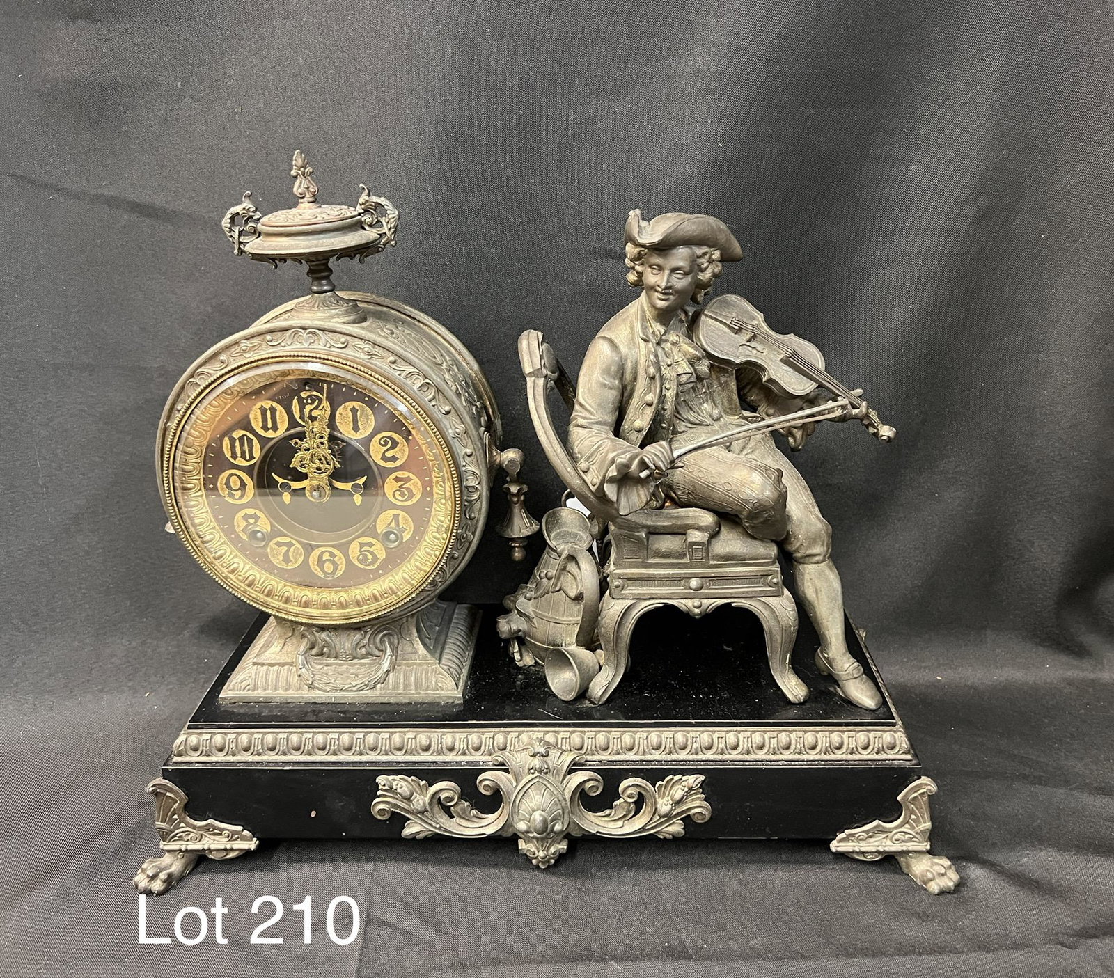 RARE Antique Late 19th Century Ansonia "Violinist" Mantle Clock: A late 1800's Ansonia "Violinist" cast metal mantle clock with statue of a seated man playing the violin. This clock has embossed numerals and open escapement. Has pendulum and key. 15" tall, 17 1/2" 
