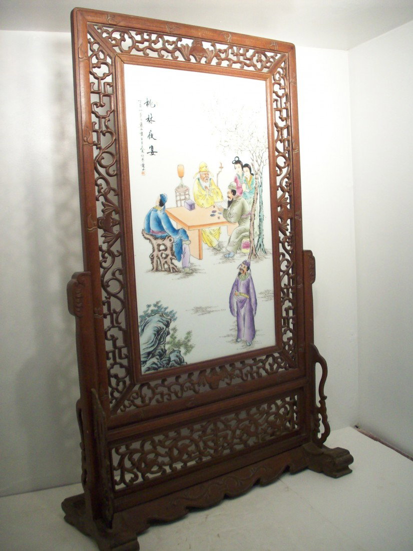 Porcelain Rosewood Screen: China. 46" X 28" X 11", Large rosewood screen with a 16" X 26" porcelain panel colorfully painted scene with men sitting at a table and women watching, carved stand needs a cleaning and the base is a 