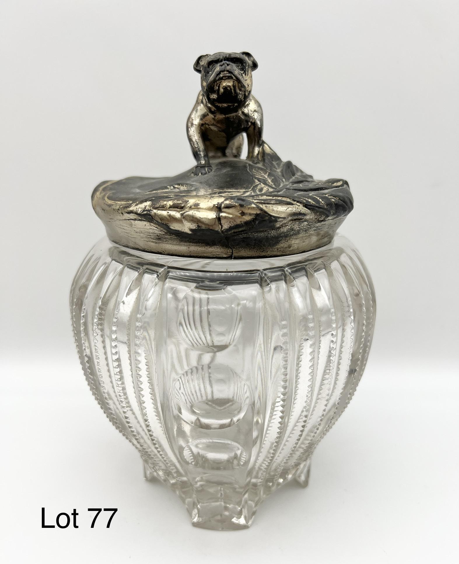 Art Nouveau Bulldog Tobacco Humidor Jar: Antique footed tobacco humidor jar comprised of pressed glass with pewter lid. The lid features a sitting bulldog at center with floral decorations surrounding. Dimensions are 8" H x 5 1/2" W. *notes-