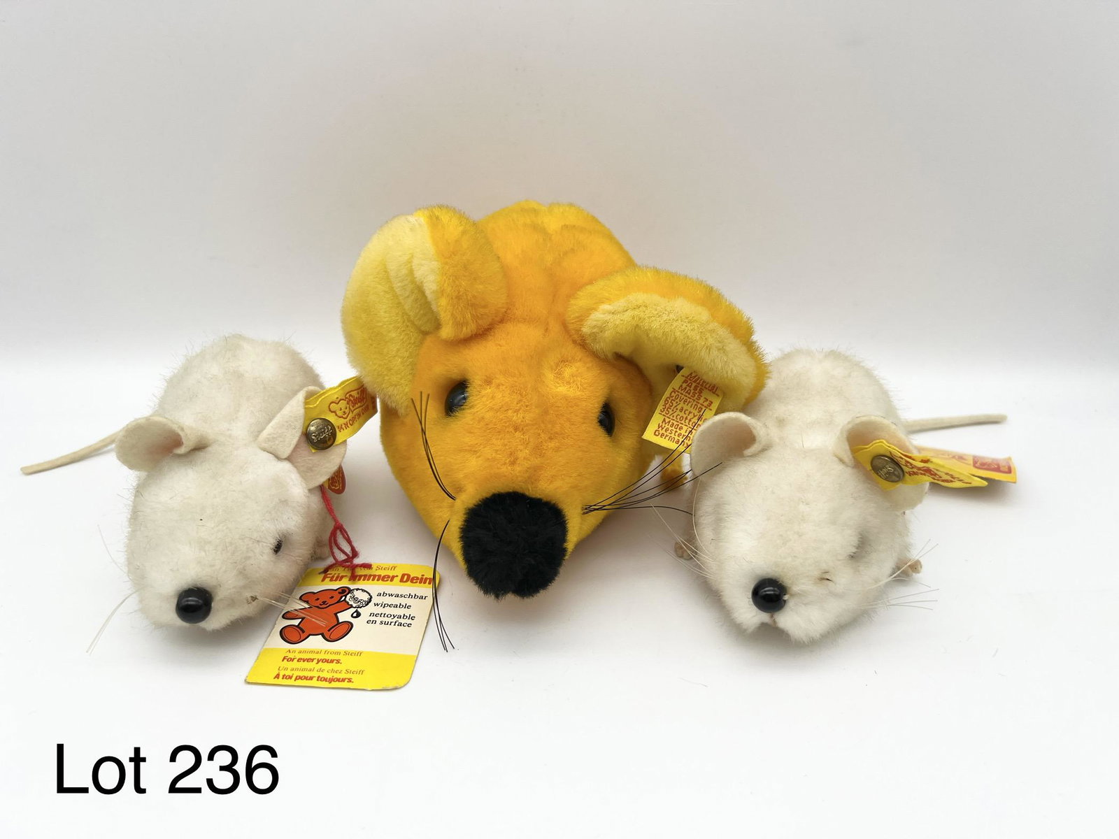 Group of Steiff Mice Plushes: Group of 3 Steiff mice plushes. Includes a yellow mouse (#5388/15) and two smaller white mice (#2170/10). Yellow mouse has button with tag. White mice have all tags and buttons. Larger mouse is 7" x 4