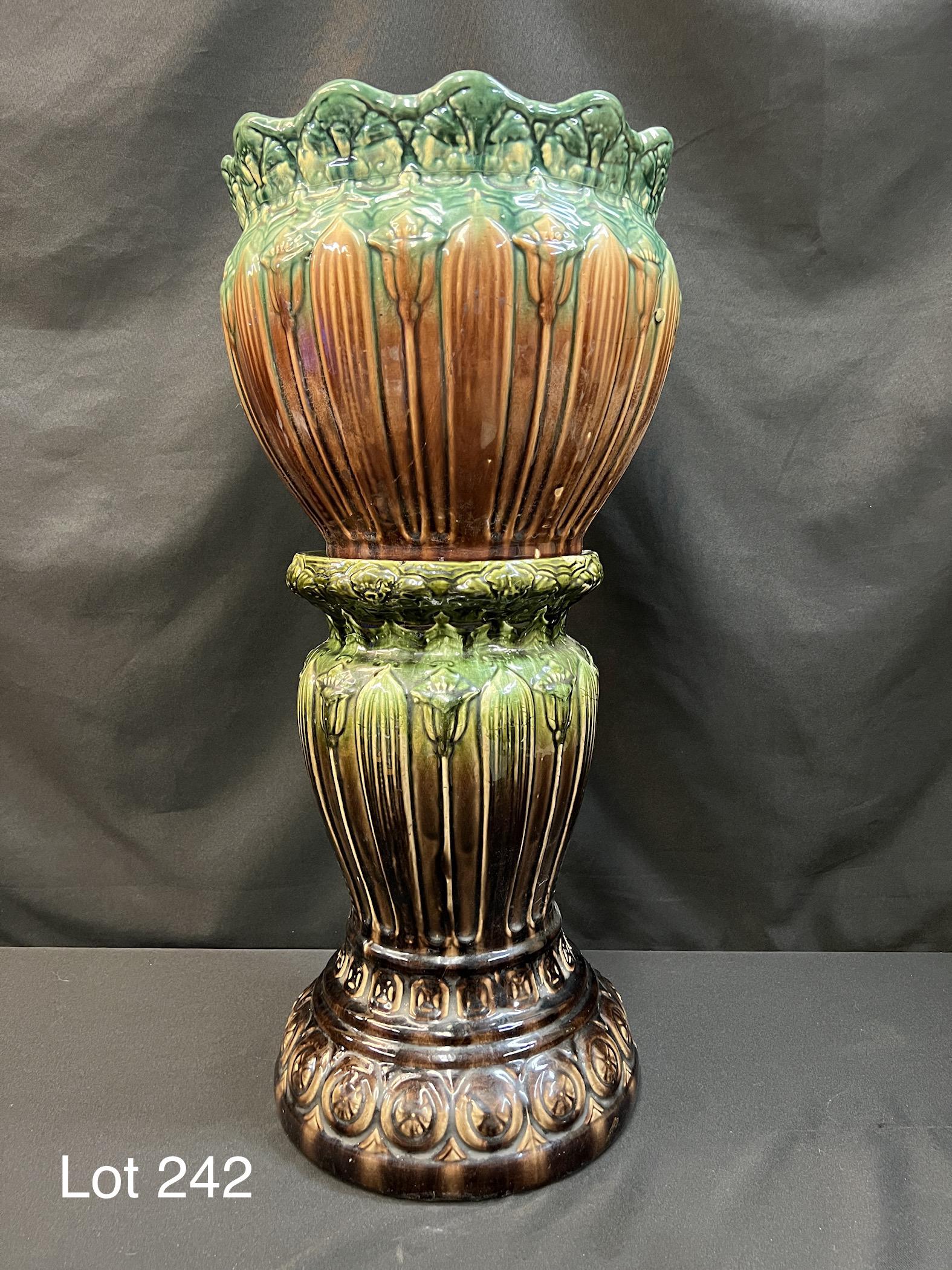Early 20th Century Jardiniere and Pedestal: Antique pottery jardiniere and pedestal with green and brown brush glaze. Decorative lillies wrap around the center of both. Dimensions are 28" H x 13" L x 13" D. *notes- chipping on both.