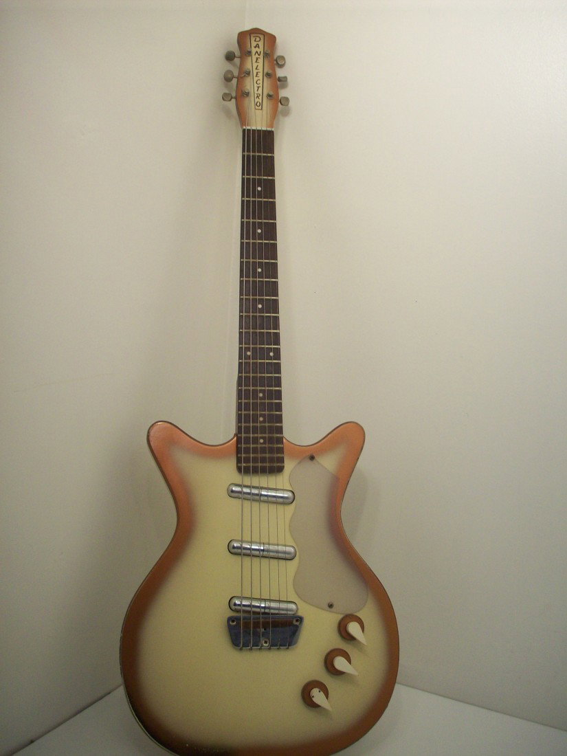 Danelectro 1950's Deluxe Shorthorn Model w/ Hard Case: 1958-1959, Shorthorn models replaces the "U" models and now has a double cutaway body with short horns. Masonite/poplar frame bodies, 13.25" wide. This Deluxe model has pointed concentric control knob