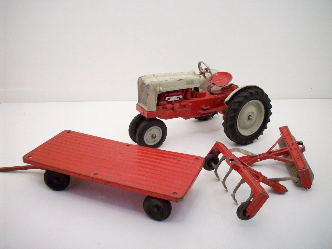 Hubley Farm Set Tractor & Implements: Large Hubley 1950's gray and red toy Ford tractor with plow, cultivator that attach and can be raised and lowered, and a farm wagon, all are in lightly played condition with paint loss