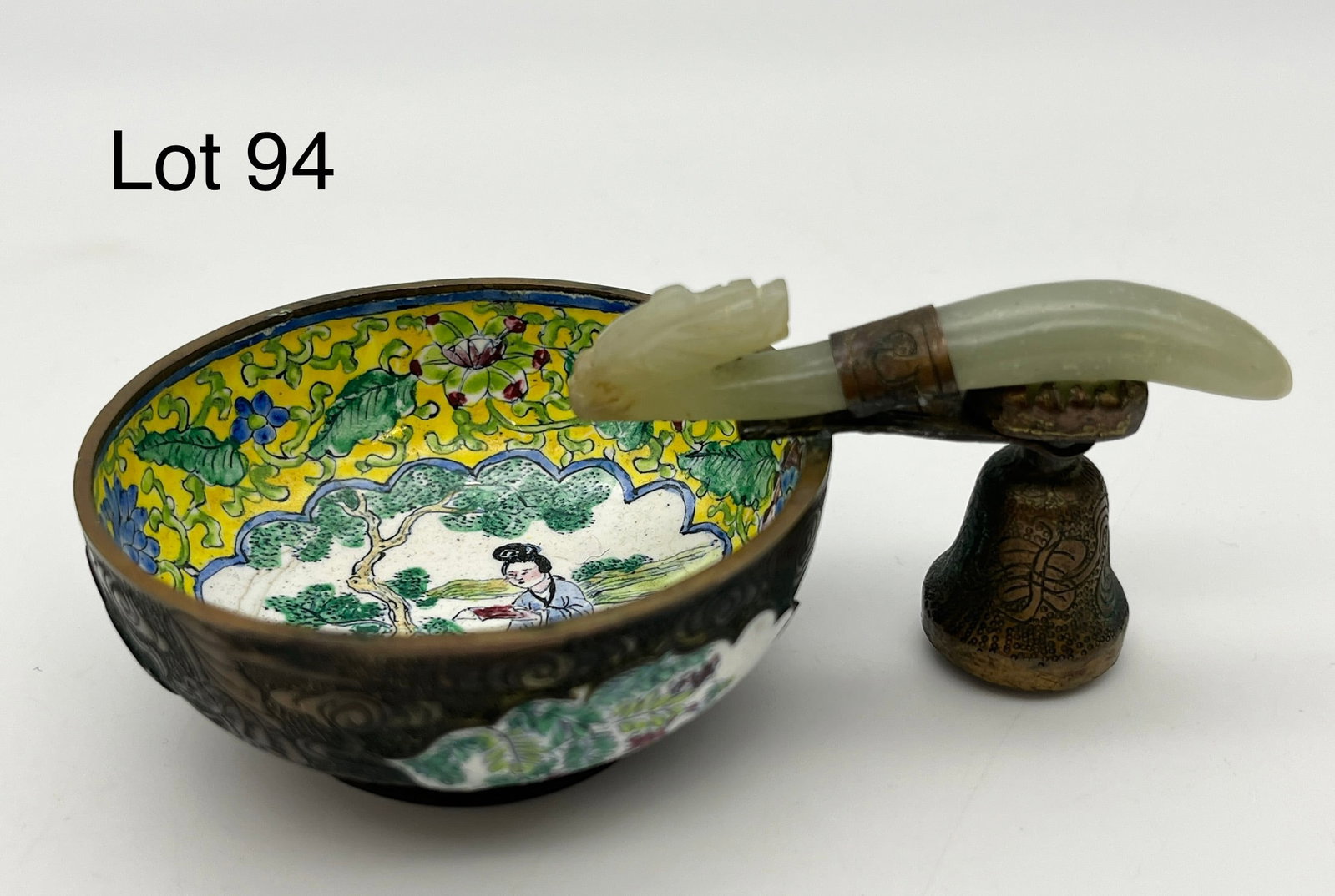 Antique Chinese Enameled Wine Cup with Jade Belt Hook Handle: An antique Chinese brass enameled wine cup with a jade belt hook handle made after a dragon. Inside shows a woman sitting in a garden, painted throughout and etched with designs on the brass itself. P