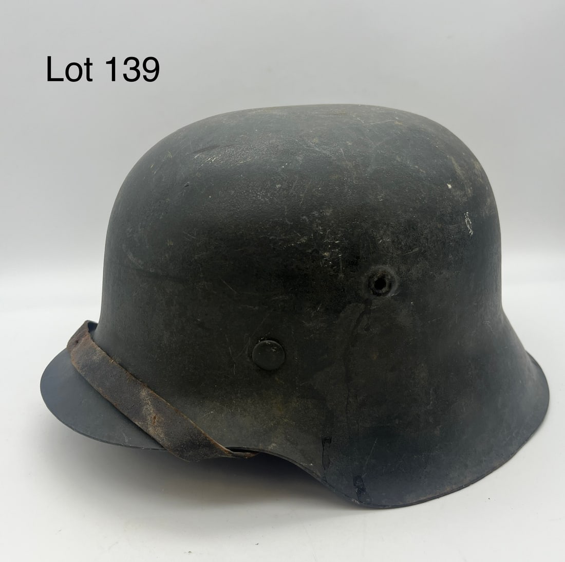 WWII M42 German Helmet: A WWII Nazi German model M-42 combat helmet in excellent condition with well-kept liner and leather chinstrap. Serial number at back rim. *note - patina from storage