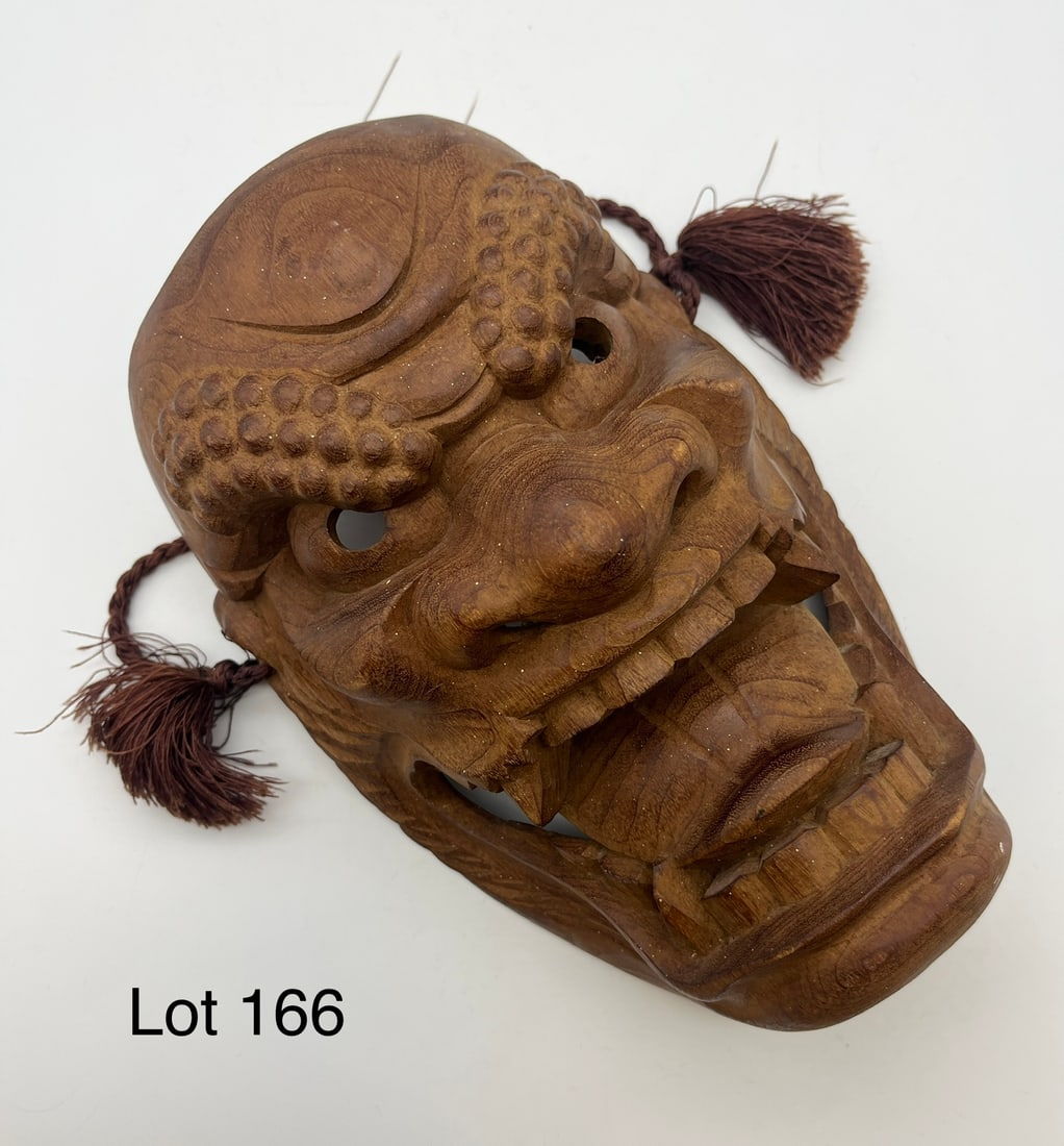Vintage Carved Wooden Japanese Demon Mask: A vintage hand carved figural Japanese mask of a demon, likely a "Menburyu Mask". Unpainted, detailed carving with pointed teeth and flared nostrils. Freestanding, with hanging rope on back. Piece mea