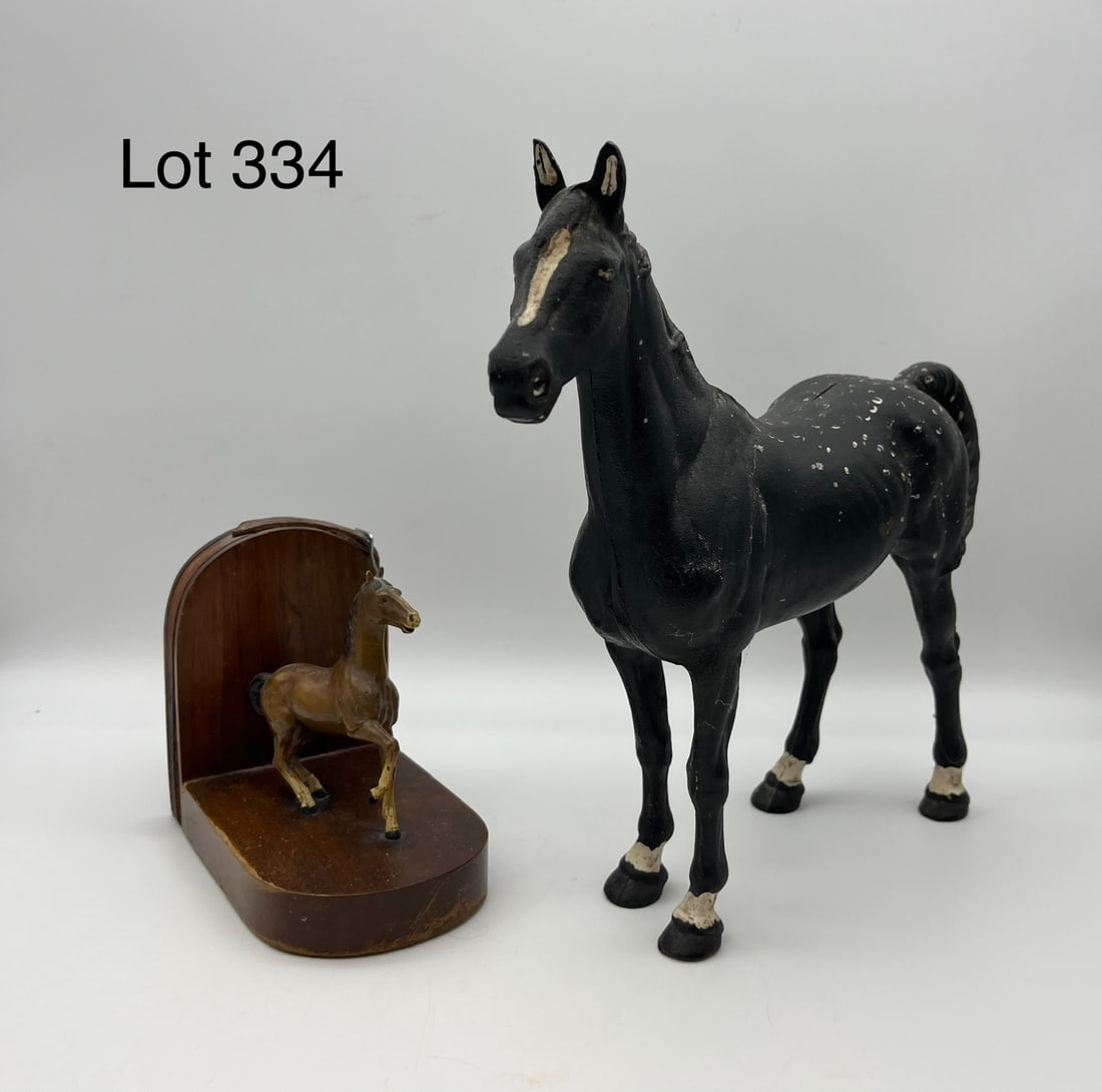 Duo of Cast Iron Horses: A duo of cast iron horses, including: a small cast iron horse bookend with a leather belt at the arch, and a Hubley cast iron horse in black aside from white painted accents. Seam along the center of