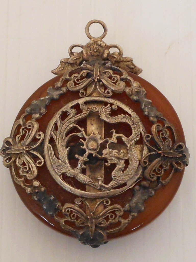 Jade Pendant in a Pewter Frame Qing Dynasty: 1 7/8" round X 1/2" thick, brown jade in a pewter frame decorated with dragons, phoenix, butterflies and flaming balls, from the Daogung Emperor reign 1821-1850 AD, great condition. 200 cts.