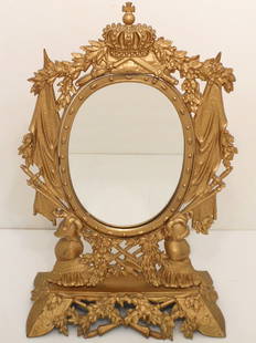 Gilt Metal Girondelle Tilt Mirror: 21" tall X 13" wide X 6 1/2" deep, titling oval mirror on a gilt metal frame and stand , decorated in a middle ages motif with crowns, Knights, swords and shields. Unmarked, circa is turn of century,