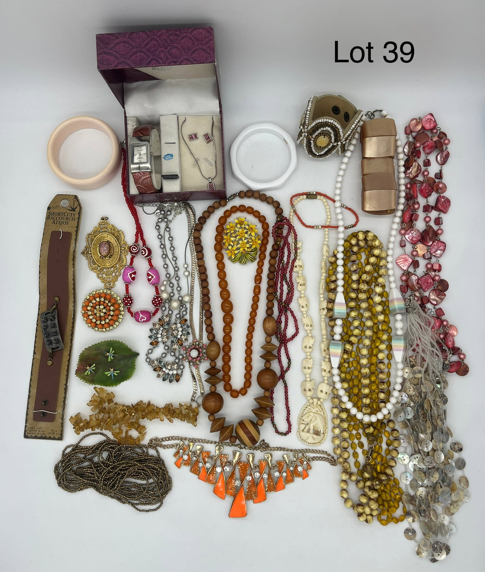 Mixed Lot of Costume Jewelry in Warm Tones: A mixed lot of costume jewelry featuring pieces in warm, natural tones. Notable pieces include a carved Elephant pendant necklace, a white Monet bangle bracelet, a Paul Jardin "Bliss" wristwatch, and 