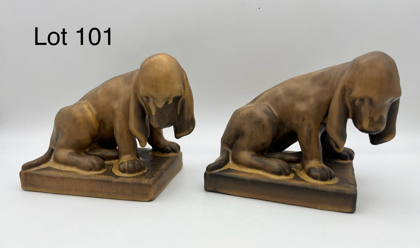 1929 Pair of Rookwood Brown Dog Bookends #2998: A pair of 1929 Rookwood dog bookends featuring cute, slouching Basset Hounds in brown glaze. Each measures 6" x 4 3/4" x 3 1/2". Makers marks underneath, with mold #2998 and cast cipher of artist Loui