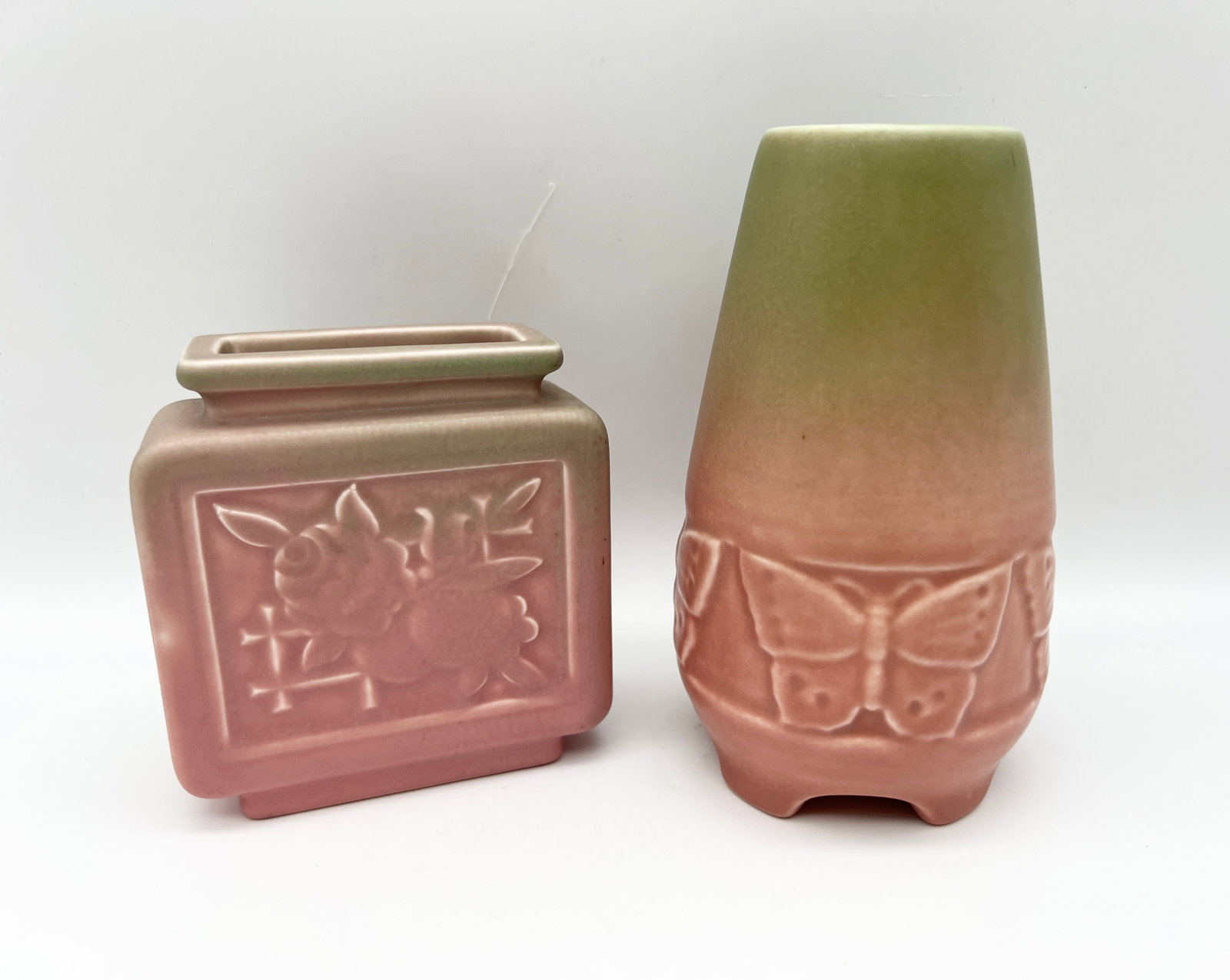 Two Pink/Green Glaze Rookwood Vases: A lot of two Rookwood cabinet vases with matte green over pink glaze. Includes a 1917 footed vase with butterfly motif (mold #2072) marked "P" for soft porcelain and a 1934 square shaped vase with ros