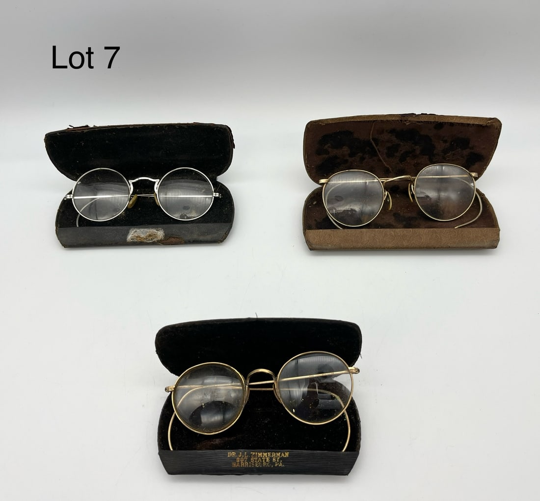 Trio of 12K Gold Filled Antique Glasses: A trio of 12K gold filled antique 'granny' glasses in varyings states of condition. Includes a gold tone pair with one bifocal lens in a case marked for Dr. J. L. Zimmerman, a silver tone pair with et