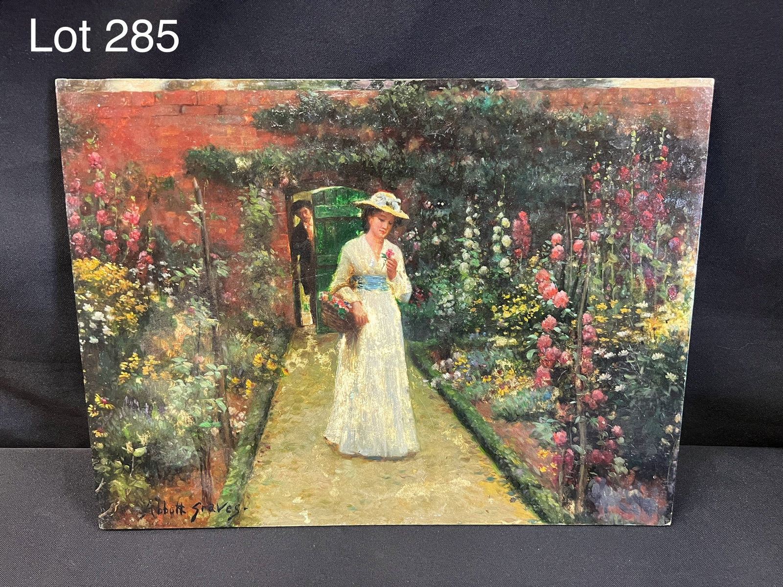 Signed Abbott Fuller Graves (1859-1936) Oil on Board of Lady in Garden: Signed Abbott Fuller Graves (1859-1936) oil on board of a lady walking through a garden path with a man peering at her behind a green door. Signature at bottom left. Dimensions are 16" x 12".