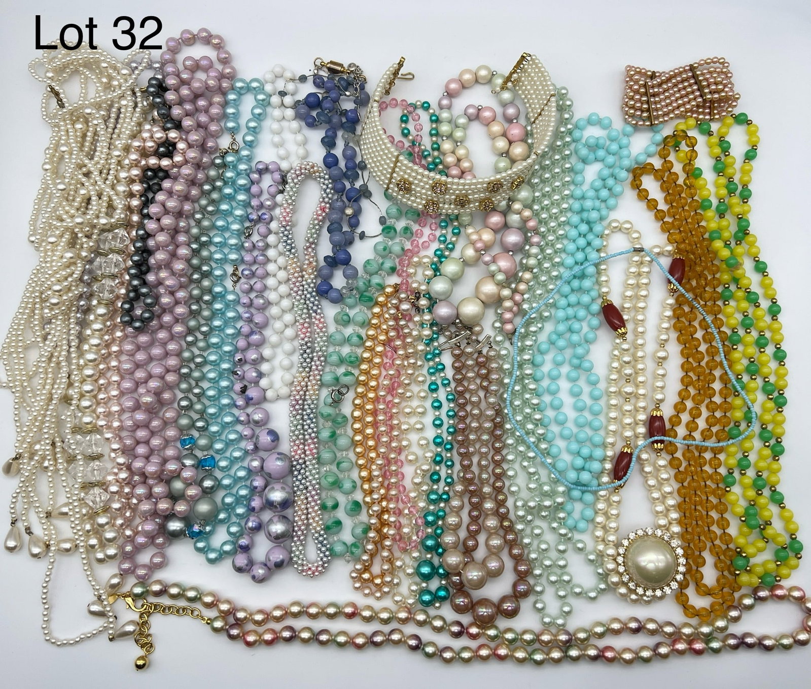 Group of Faux Pearl and Beaded Costume Jewelry: A wide range of colorful faux pearl and beaded costume jewelry. Notable items are a faux pearl choker necklace with pink rhinestone flowers and a a strand of faux amber beads.