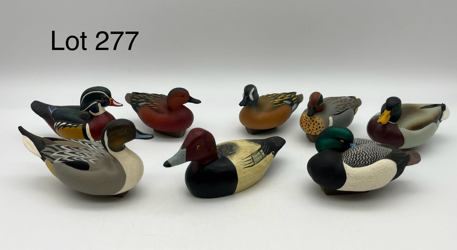 Collection of Miniature Duck Decoys Featuring Jett Brunet: A collection of eight miniature duck decoys, most of which are attributed to Jett Brunet of Ducks Unlimited and dated 2000-2007. Includes Mallards, Wood Ducks, Bluebills, and more. Also includes a rep