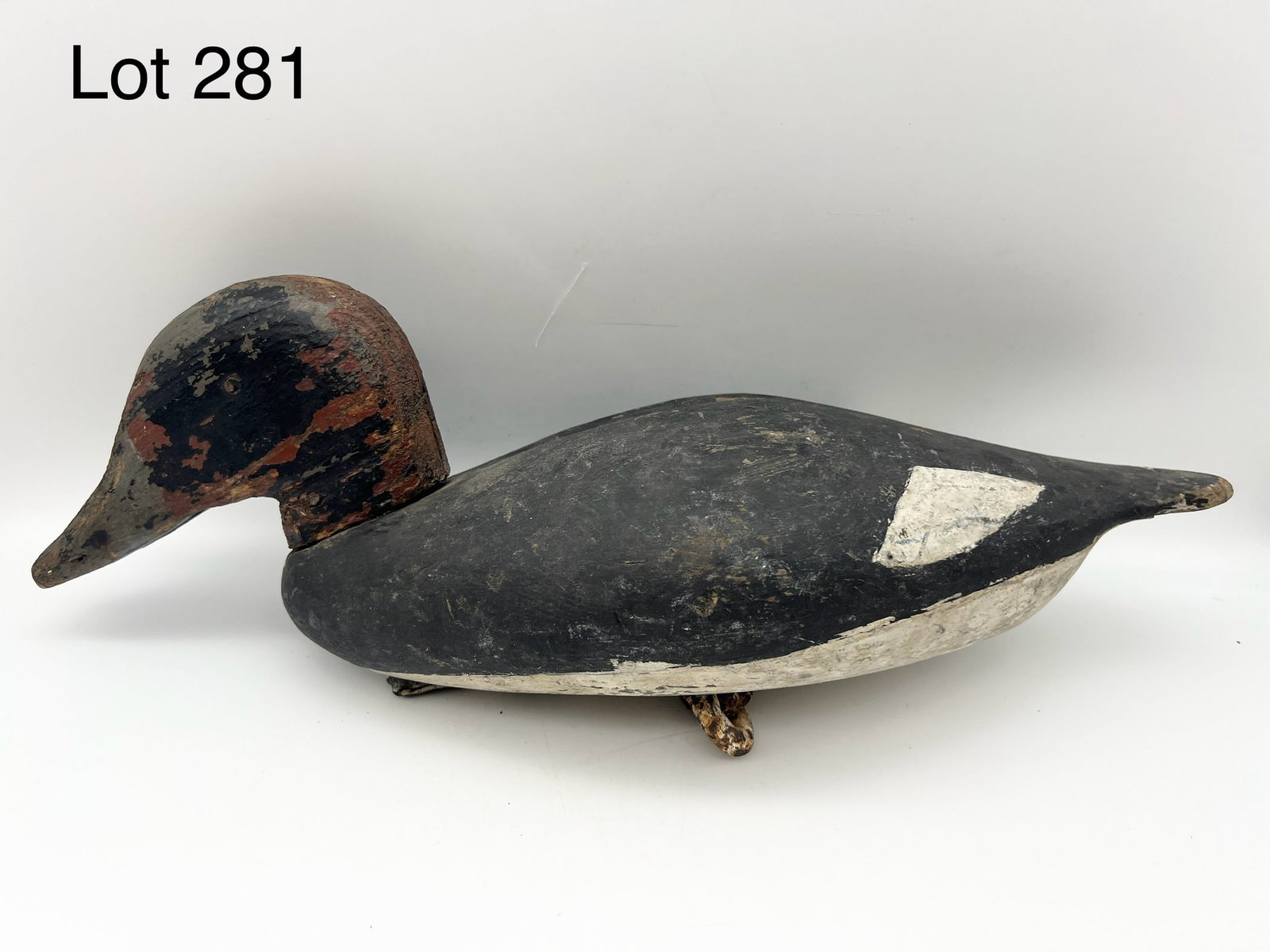 Antique Duck Decoy: An early carved wood duck decoy. Painted with red head, black body, graybill and white tipped wings. Measures 16" long. *notes- wear, patina throughout.