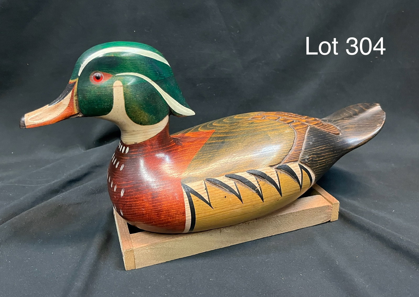 Carved Wood Duck Decoy by Tom Taber: An excellent condition Wood Duck decoy with glass bead eyes. Detailed painting and carved feathering, artist signature from Tom Taber underneath, comes on small wooden base. Measures 14"