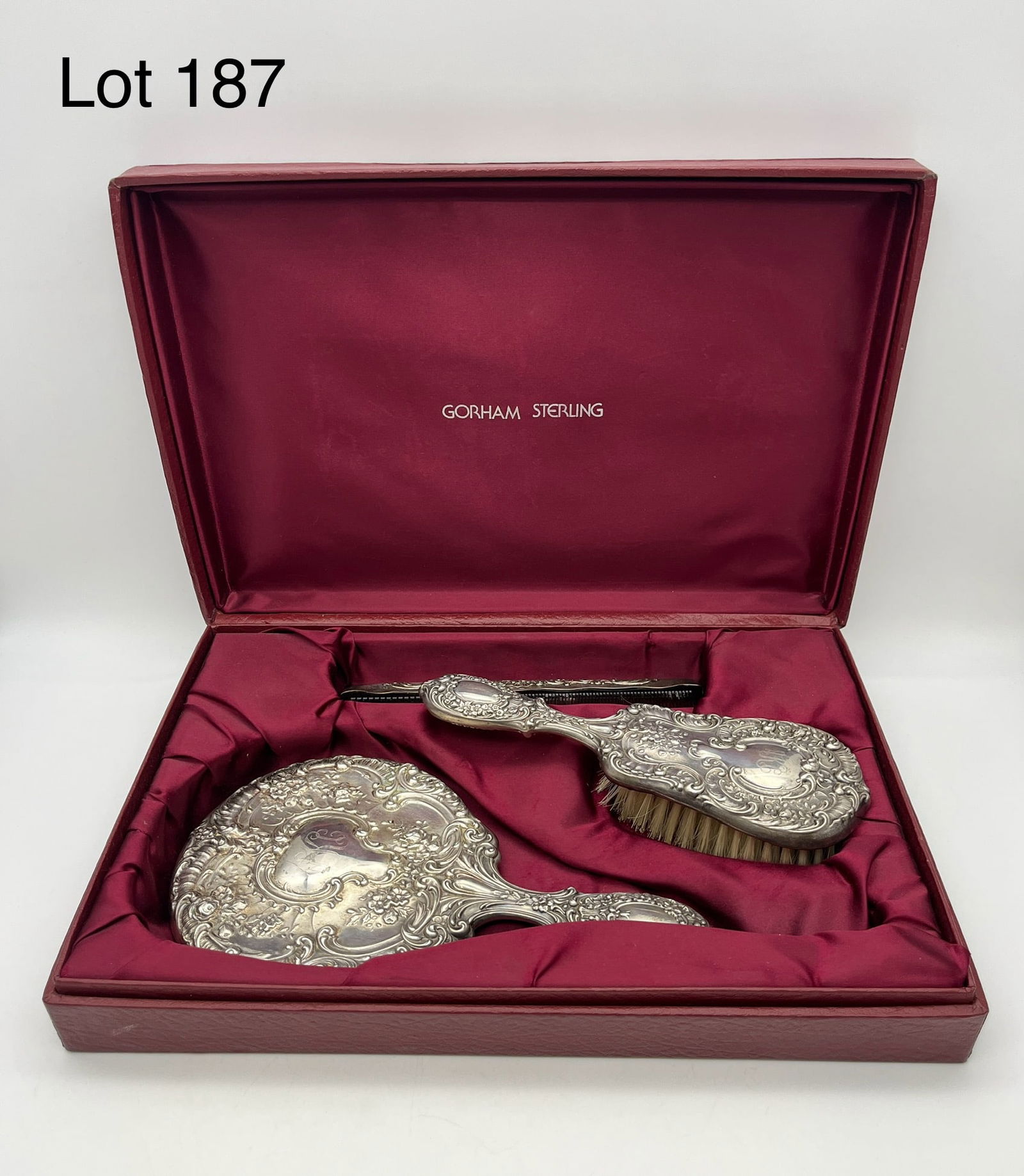 Gorham Sterling Dresden Rose Pattern Vanity Set: A three-piece 'Dresden Rose' pattern sterling silver vanity set by Gorham, including a hand mirror, brush, and comb. Monogram "AKC" with the name "Andrea" at handles. Well kept in original case measur