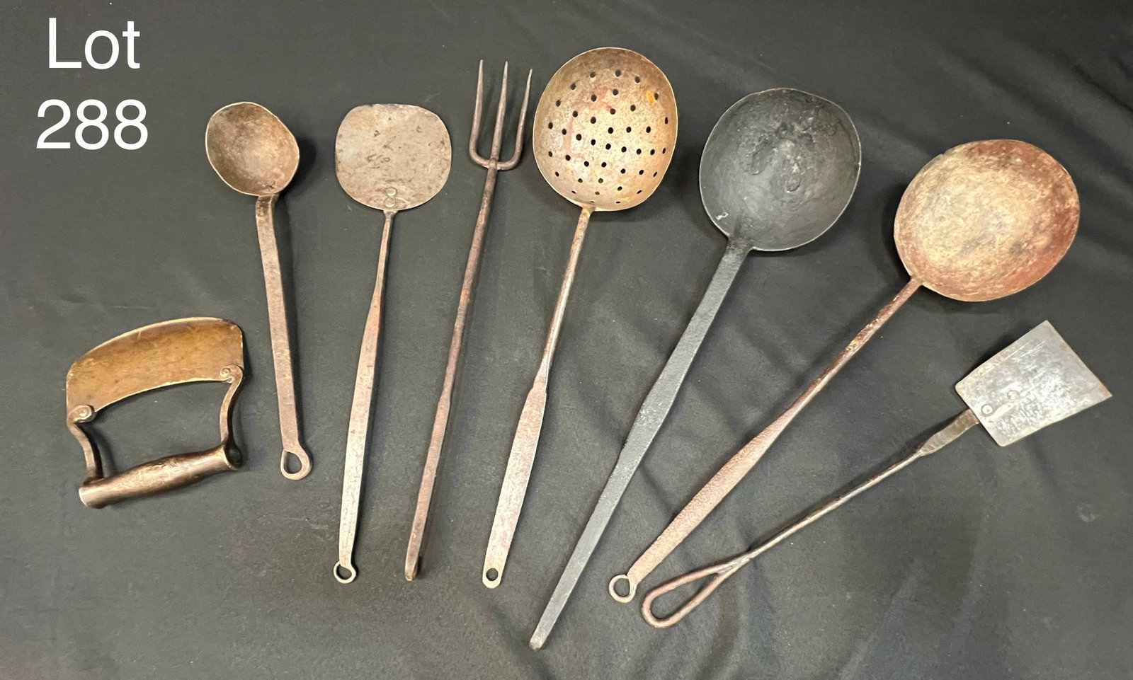Collection of Primitive Kitchen Utensils: A group of antique primitive kitchen utensils. Includes spoons, spatula, three prong fork and slicer. Longest is 19". *notes- patina