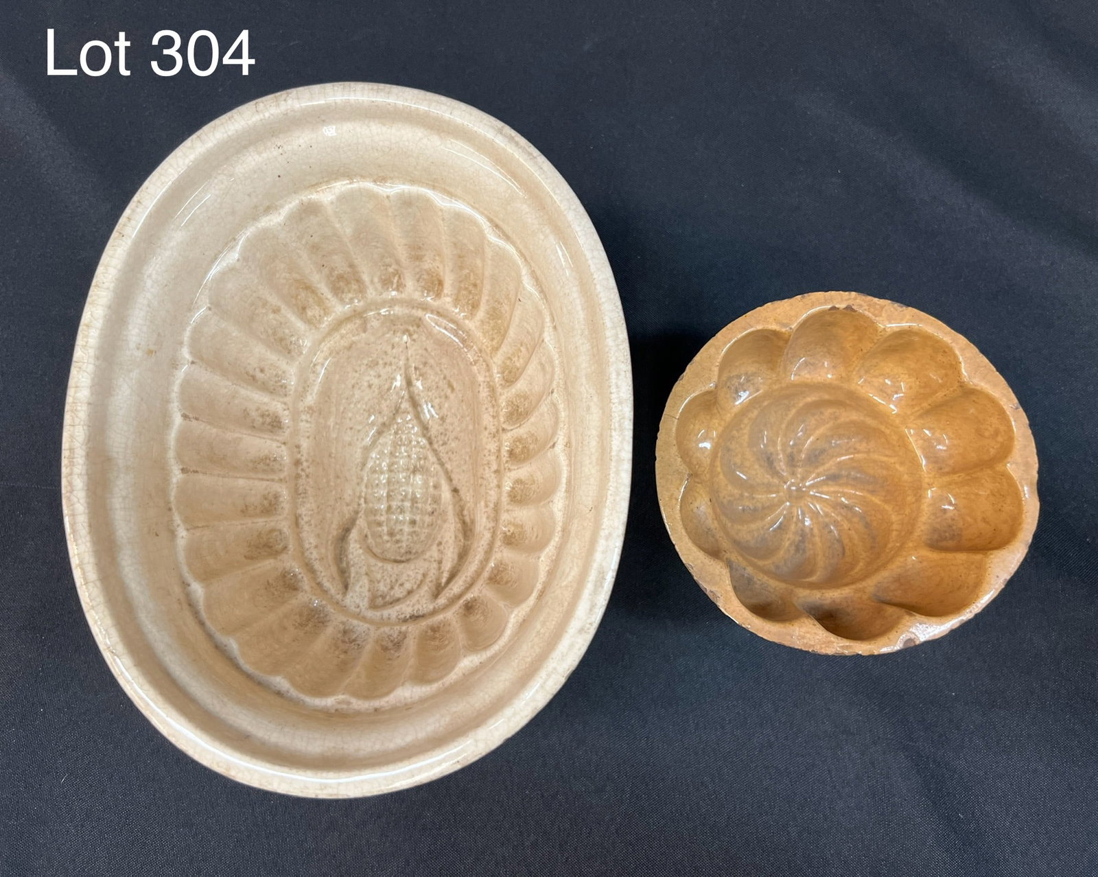 Duo of Antique Stoneware Food Molds: Turn of the century stoneware food molds. Includes a 8 1/2" x 6 1/2" x 4 1/2" mold with corn design and a smaller mold measuring 3" x 5" with pinwheel design. *notes- wear, cracking