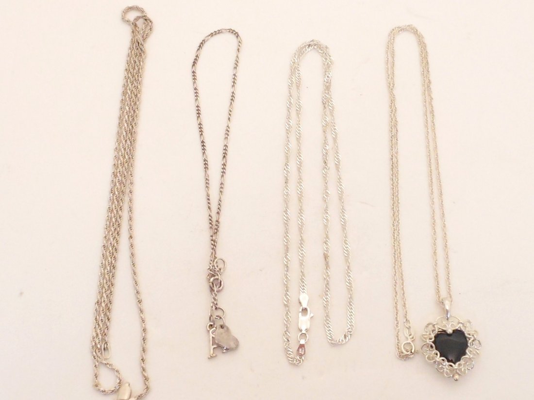 Lot of 4 Pieces of Sterling Silver Jewelry: Three Sterling Silver Necklaces, One with a heart pendant and black stone. One necklace is missing a piece on the chain that connects to the clasp. One Sterling Silver Bracelet/Anklet with charms. All