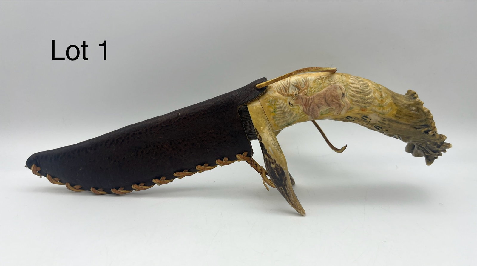 Handmade Antler Knife with Damascus Blade: A large-sized knife that features a finished antler haft adorned with deer carvings. Two full deer carved at the side and butt of the antler, with decorative hoof tracks trailing along one of the pron