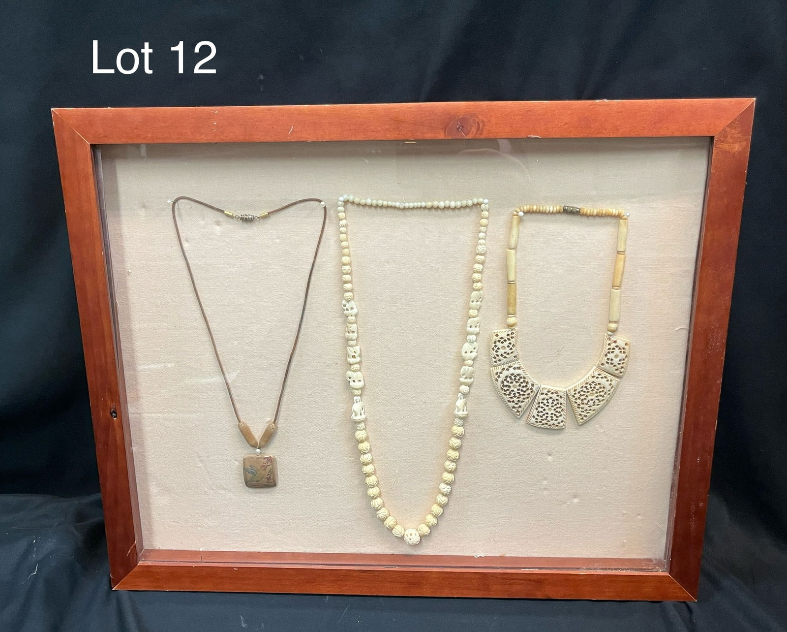 Three Necklaces of Bone, Ivory, and Fossil Ivory: A set of three handmade necklaces made from bone, ivory, and fossil ivory. From left to right, this collection shows a mastodon ivory pendant with hummingbird, a beaded bone necklace with small elepha