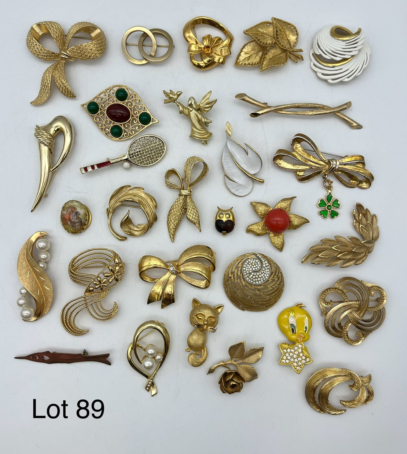 Signed Costume Jewelry Brooches in Gold Tones: A lot of signed costume jewelry brooches in gold tones, showing designers like Avon, CastleCuffe, Coro, Monet, and Giovanni.