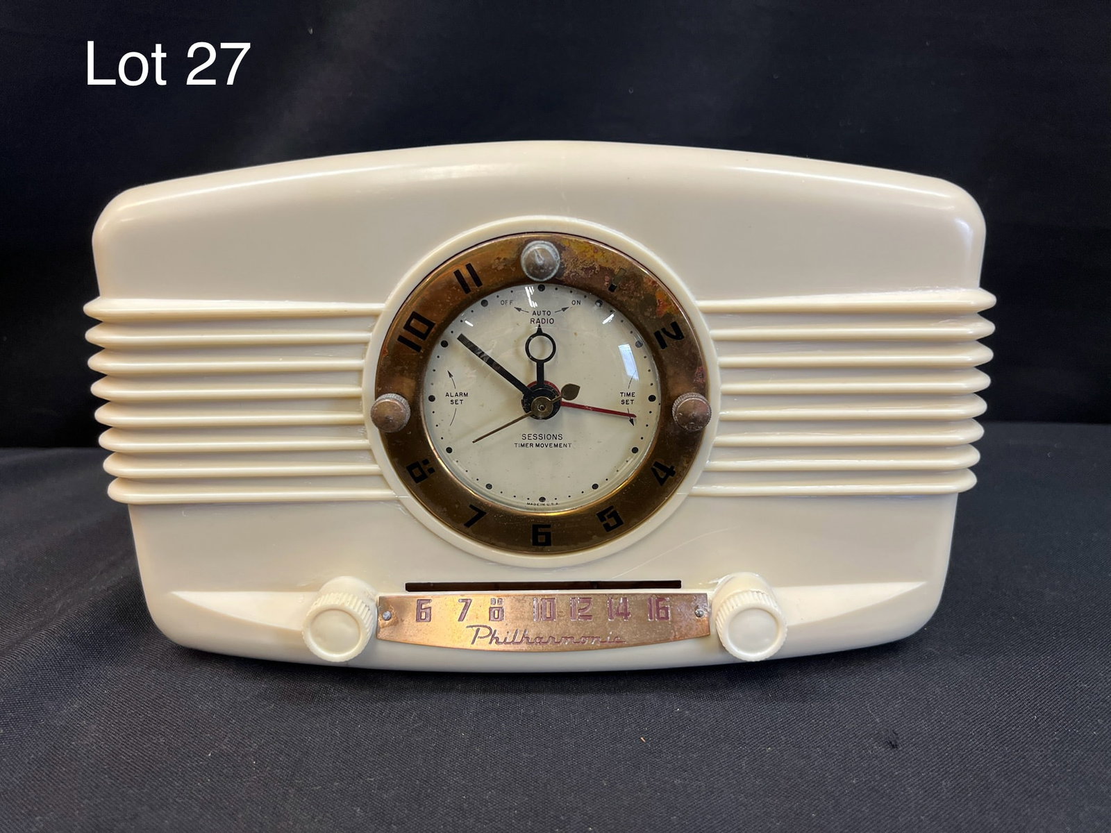 1951 Philharmonic 51C3A Tube Radio: A 1951 Philharmonic 51C3A tube clock radio. Clock at center with slide dial at bottom. Two knobs. Serial #14843.