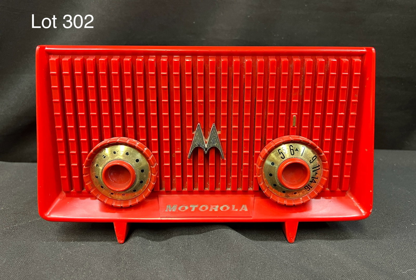 1953 Motorola 56R Red Tube Radio: A 1953 Motorola 56R tube radio in red. Front grill with metallic "M" logo at center, 2 knobs and feet.