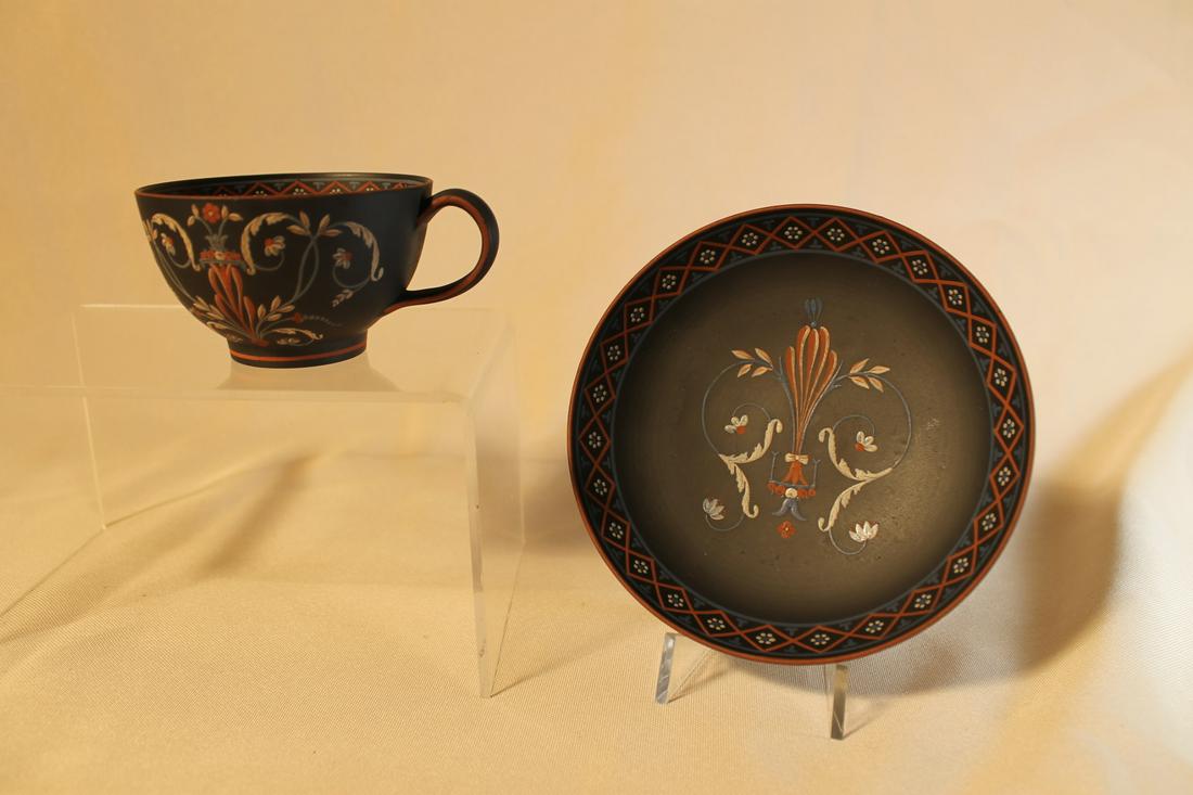 Black basalt with encaustic painting, impressed mark on: Black basalt with encaustic painting, impressed mark on underside and number. 5" diameter dish and 1 7/8" tall tea cup