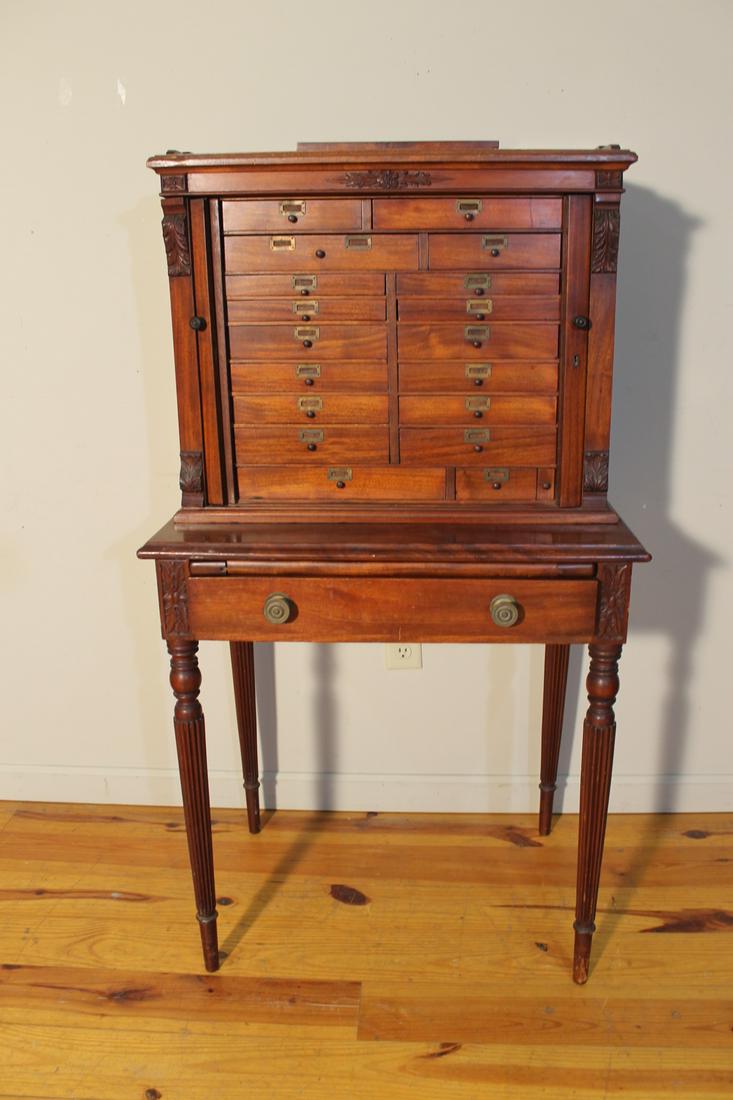 Mahogany Tambor Desk: Turn of the 20th century tambor desk fitted with 19 assorted sized draws, that sits on base which has reeded style legs with 1 draw and writing slide, 54" tall by 26 1/2".