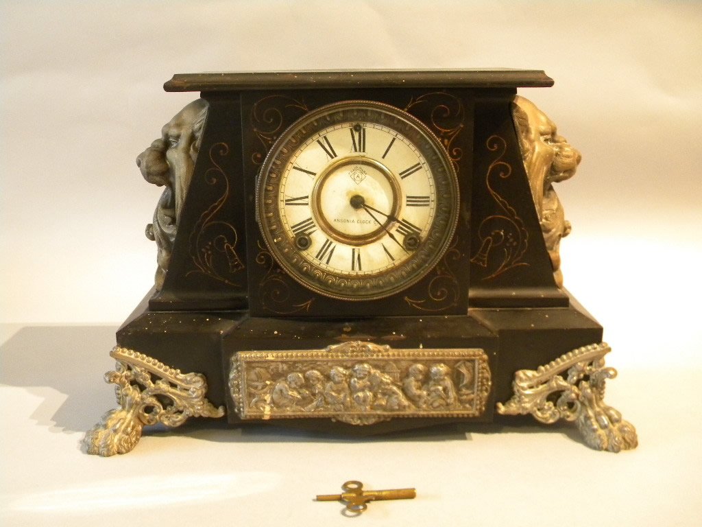 Ansonia Iron Mantle Clock: Aesthetic movement mantle clock with figural lion mounts, hairy paw feet, enamel dial, made by Ansonia clock company