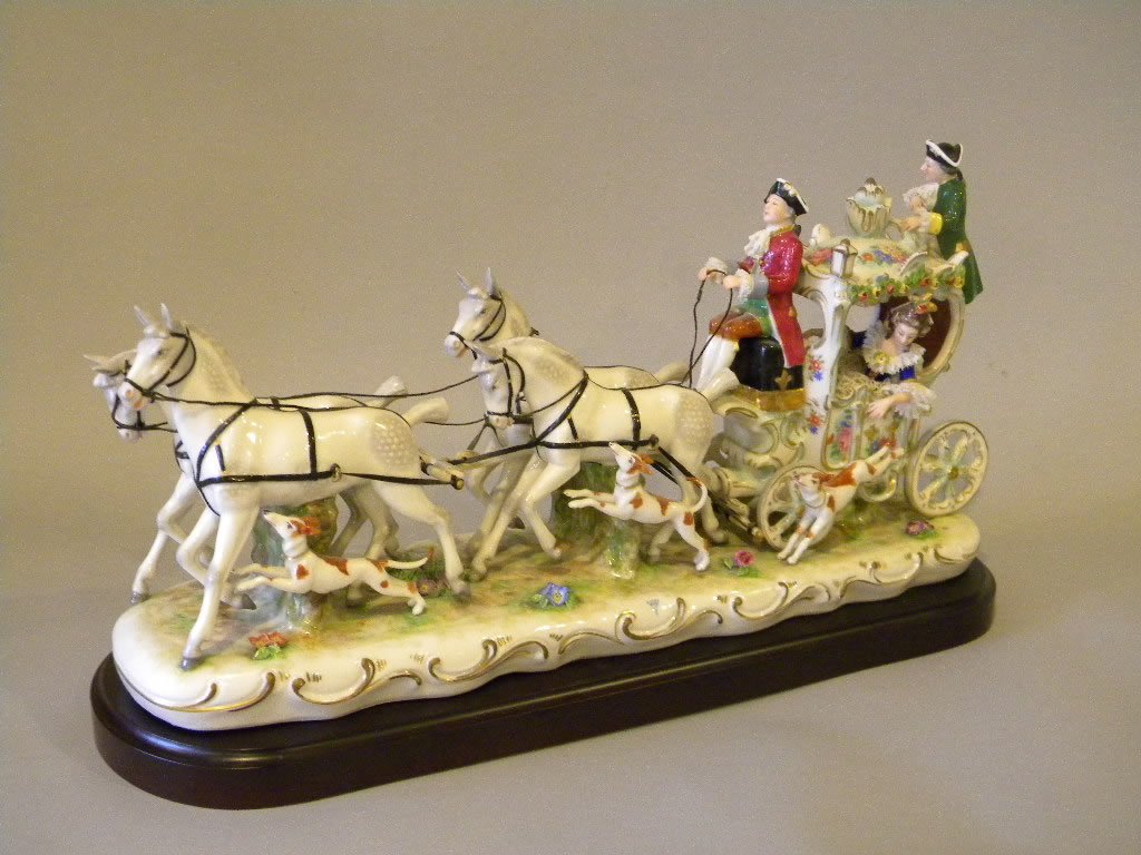Dresden Porcelain Coach: Lady with carriage, driver, 2 sets of dapple grey horses, 3 hounds and footman. 19" long by 10" tall. Comes with a wooden base to sit it on. Has the blue Dresden mark with black Made in Germany mark