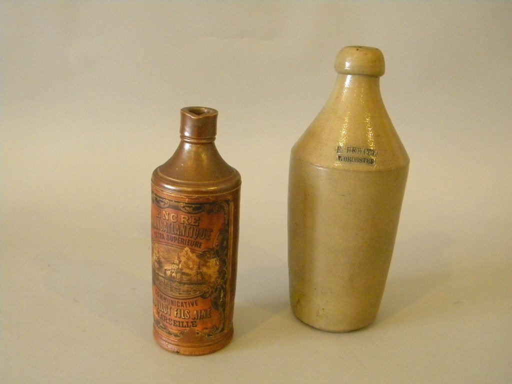 2 Stoneware Bottles: 1. 10 1/2" salt glazed E. Hewitt Worcester Bottle 2. 8 1/4" manganese bottle with French paper label