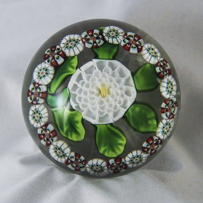 Baccarat, Antique Paperweight: Antique Baccarat paperweight. Cane 2, lampwork, flower, camomile. Miniature white camomille, 6 green leaves and stem, ring of alternating red and white arrowhead and white stardust canes, clear star c