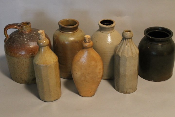 59. 7 Pcs of Stoneware: 1 manganese crock 8 1/2" 2. John Bell, Waynesboro salt glaze, [rim chip]9 1/2" tall. 3.salt glaze 9 1/2" tall 4.faceted shape bottle, fluted top. 9 3/4" tall 5. W.M. Kraas. 6. jug 9 3/4" 7. Hand plane