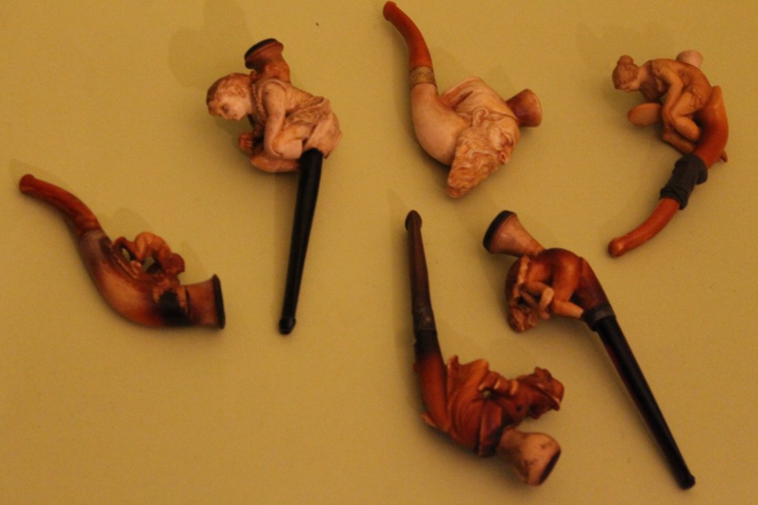 Lot of 6 Meerschaum Pipes: 1. Figural elderly man w/ beard & taselled hat, 4-1/4" 2. Child at play, 4-1/2" 3. Lady w/ hat, 5-1/8" 4. Girl sitting & smoking, 5-1/4" (damage to legs) 5. girl looking in mirror, 5" (damaged) 6. Wom