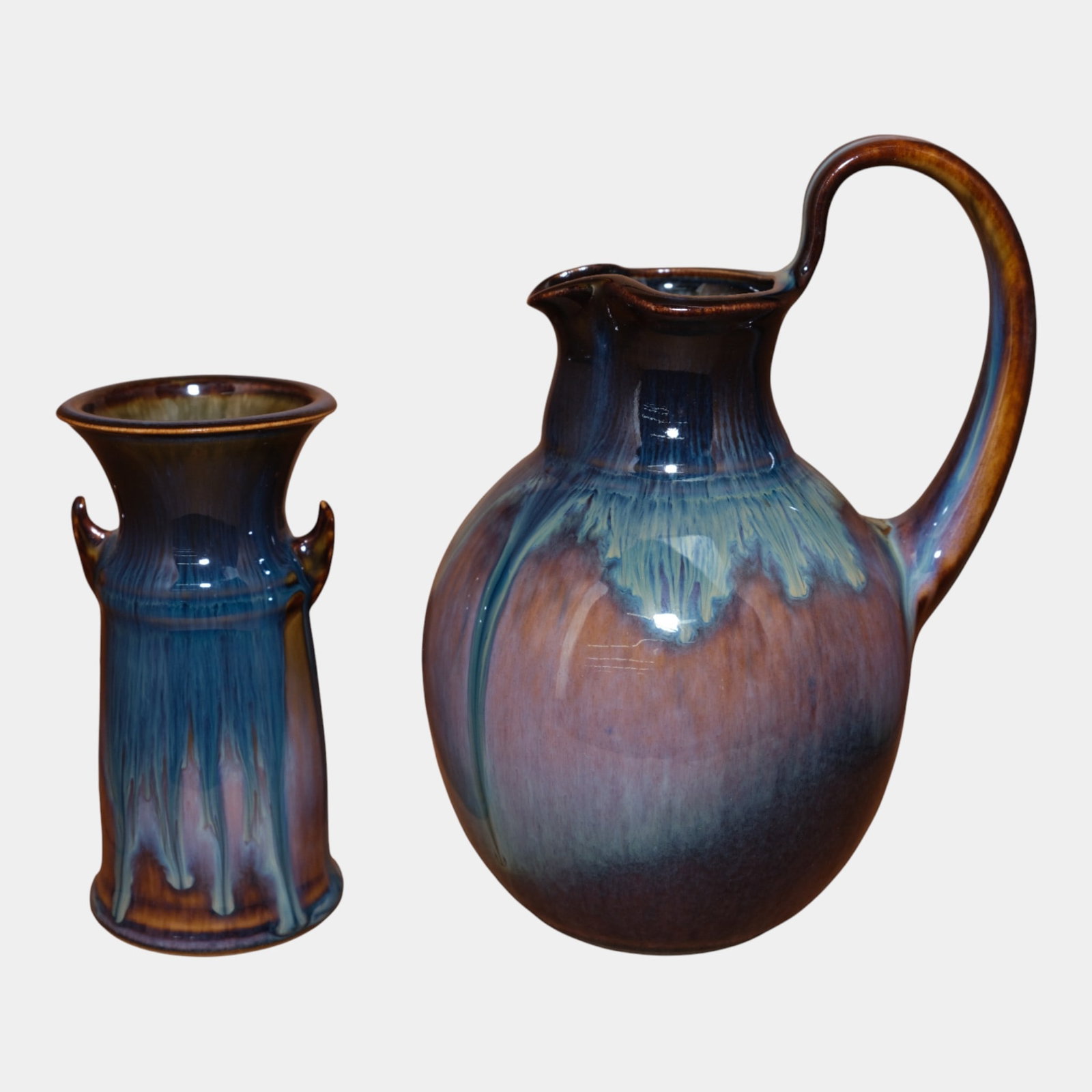 Bill Campbell Studio Art Pottery Blue Purple Drip Glaze Pitcher And Vase: Bill Campbell Studio Art Pottery Blue Purple Drip Glaze Pitcher And Vase Richly glazed and harmoniously paired, this studio pottery set by Bill Campbell features a bulbous pitcher and slender vase,