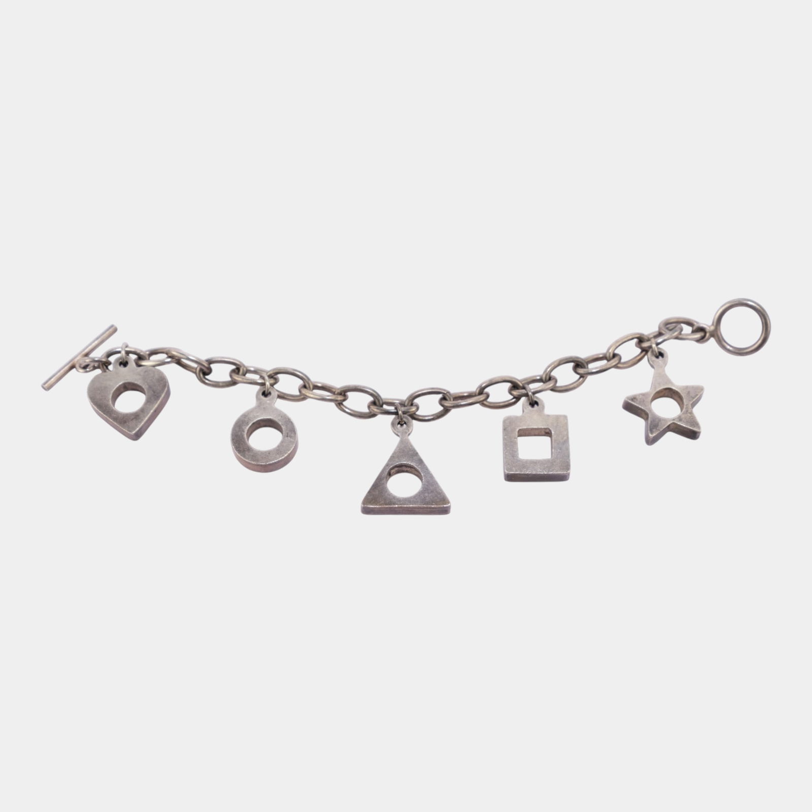Mexican Sterling Silver Modernist Geometric Form Toggle Clasp Charm Bracelet: Stylish sterling silver charm bracelet featuring a series of modern geometric forms, including circles, triangles, squares, and a star. Clean lines and balanced spacing give this piece a minimalist, m