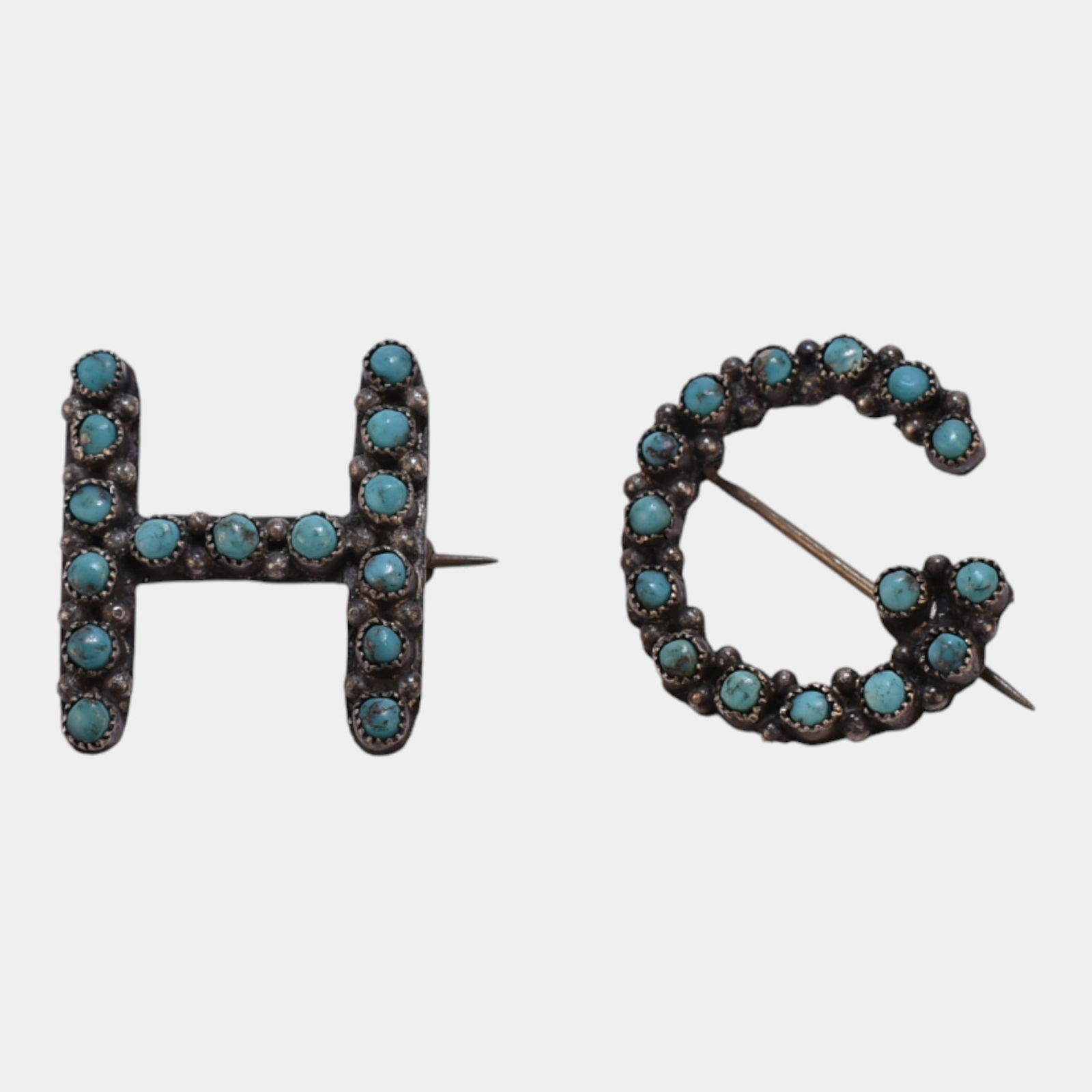 Native American Mid Century Sterling Silver Turquoise H & G Initial Brooches: Boldly graphic and finely handcrafted, these Southwestern-style initial brooches feature H and G letter forms set with vivid turquoise cabochons in sterling silver, blending playful personalization wi