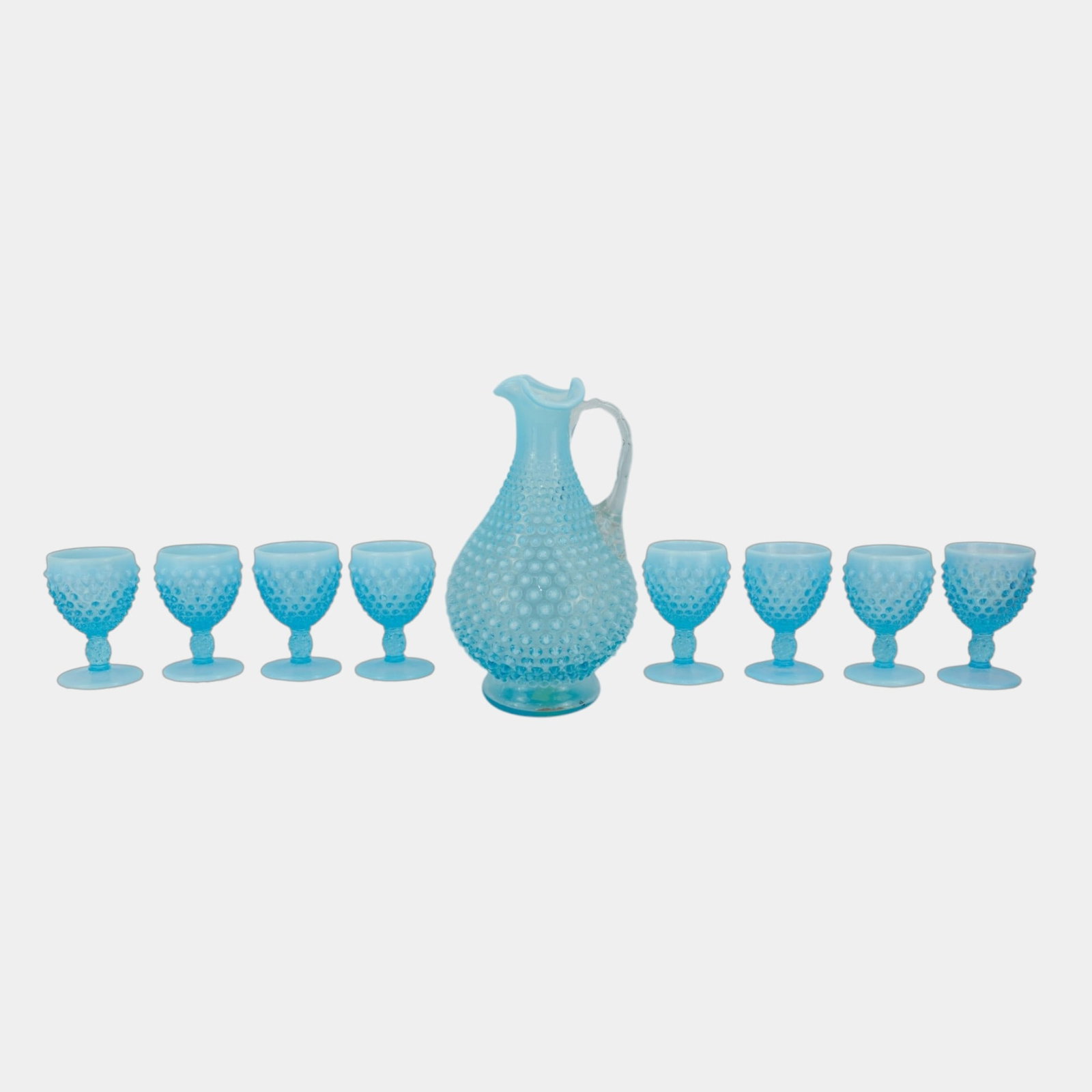 Fenton 1940s Blue Opalescent Hobnail Decanter And Eight Goblets Pedestal Glasses: Professional, fast, and affordable in house shipping available for all items. For higher resolution images please visit bid.craftedauctions.com Fenton 1940s Blue Opalescent Hobnail Decanter And Eight 