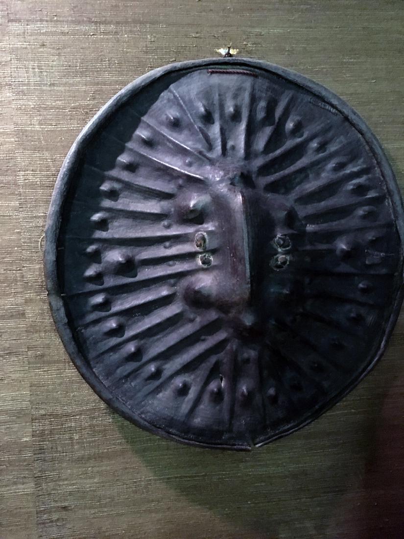 Ethiopian Animal Hide Shield: Vintage Ethiopian animal hide/leather war shield. Made by hand by mounding sand and rocks into pattern, then put wet hide on sand and rocks to dry. Measures approx. 30" wide. Was brought back from one